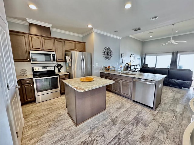 kitchen with visible vents, a center island, wood finish floors, stainless steel appliances, and a sink