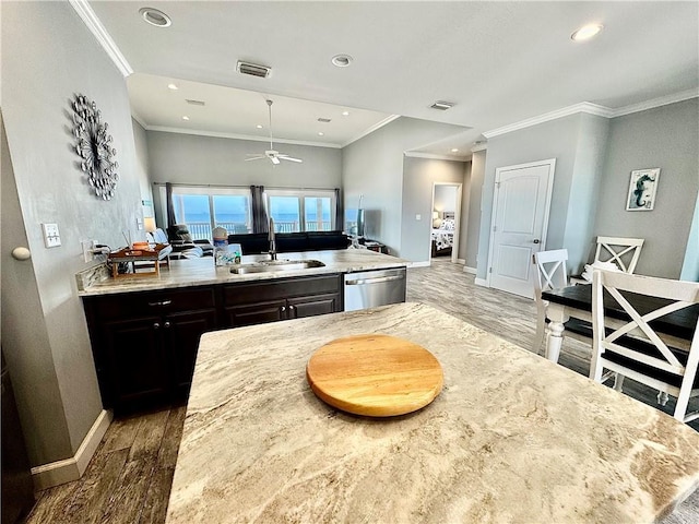 kitchen with wood finished floors, baseboards, ornamental molding, a sink, and stainless steel dishwasher