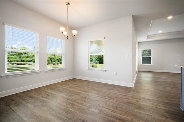 spare room featuring baseboards, a notable chandelier, and dark wood finished floors
