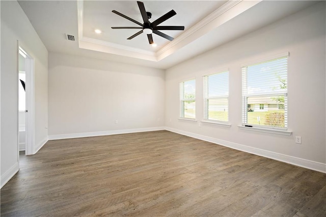 unfurnished room featuring dark wood-style flooring, visible vents, crown molding, and a tray ceiling