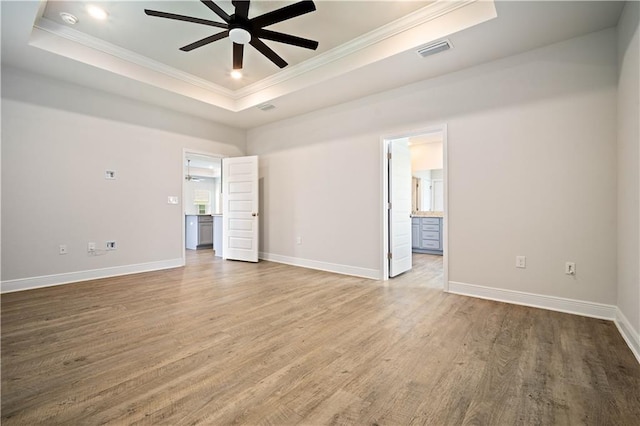 unfurnished bedroom with visible vents, a raised ceiling, wood finished floors, and crown molding