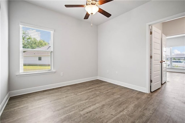 unfurnished room with wood finished floors, a ceiling fan, and baseboards