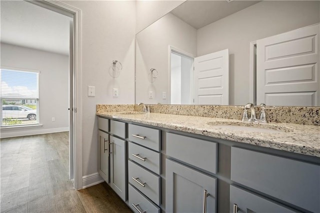 full bathroom with double vanity, wood finished floors, baseboards, and a sink