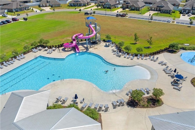 community pool with a lawn, a water slide, and a residential view