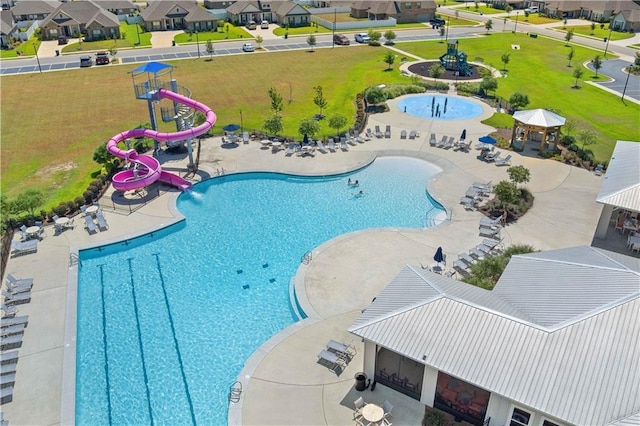 community pool featuring a water slide, a patio area, and a residential view