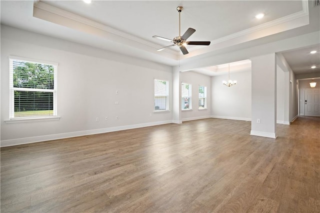 unfurnished living room with wood finished floors, a raised ceiling, crown molding, and baseboards