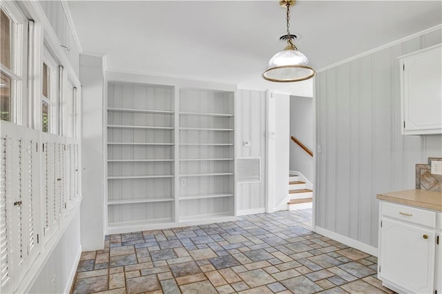 1215 Anchor Dr, Mobile, AL 36693 - unfurnished dining area featuring stairs, stone tile floors, baseboards, built in shelves, and ornamental molding