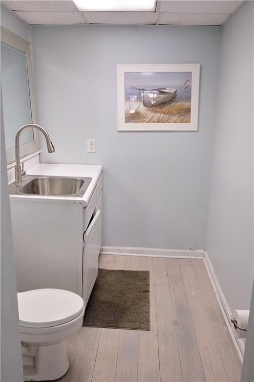 bathroom featuring hardwood / wood-style floors, toilet, vanity, and a paneled ceiling