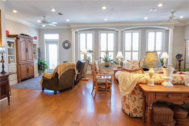 living room with ornamental molding, ceiling fan, decorative columns, and light wood-type flooring