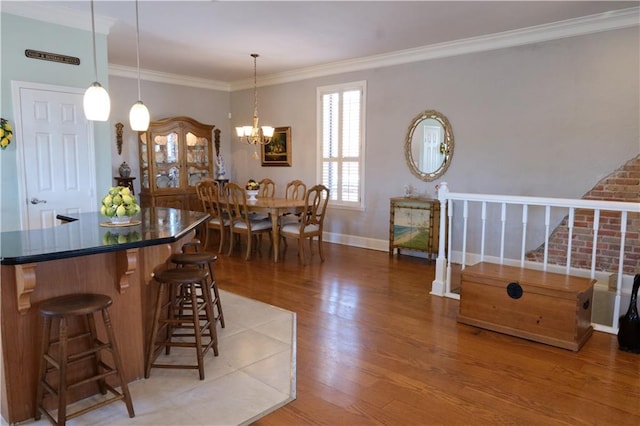 dining room with ornamental molding, wood-type flooring, and a chandelier