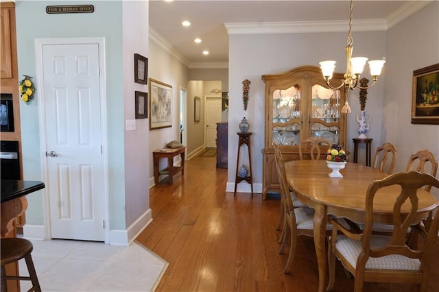 dining area featuring an inviting chandelier, light hardwood / wood-style flooring, and ornamental molding