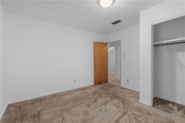 unfurnished bedroom with light colored carpet and a closet