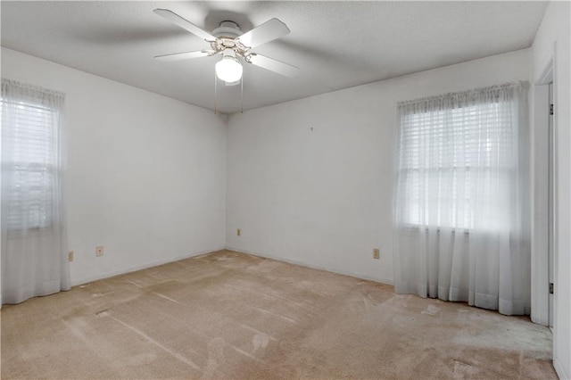 carpeted spare room featuring a wealth of natural light and ceiling fan