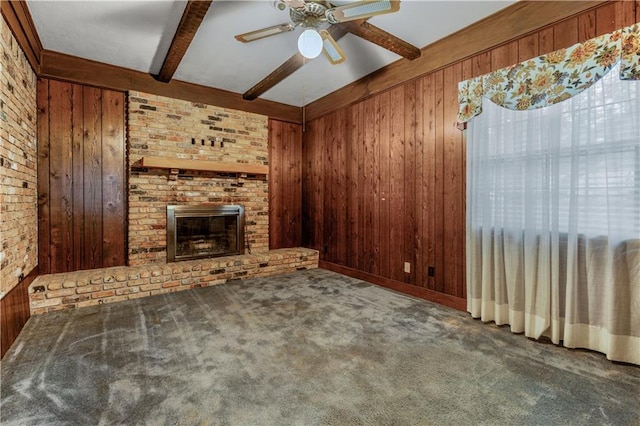 unfurnished living room featuring wood walls, beam ceiling, and a brick fireplace