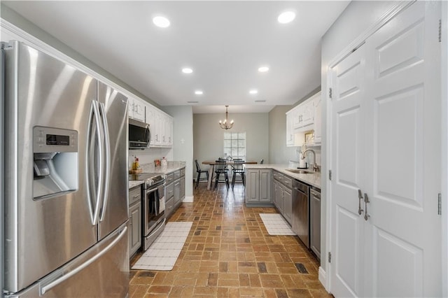 kitchen featuring gray cabinetry, stainless steel appliances, sink, white cabinets, and hanging light fixtures