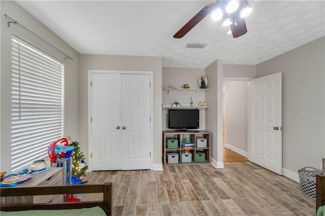 bedroom with ceiling fan, a closet, a textured ceiling, and hardwood / wood-style flooring