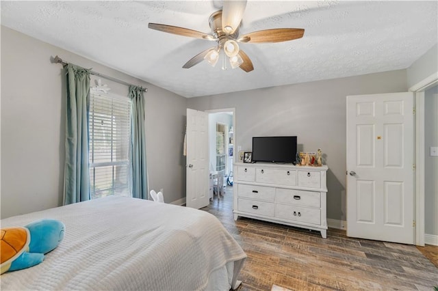 bedroom with ceiling fan, dark wood-type flooring, and a textured ceiling