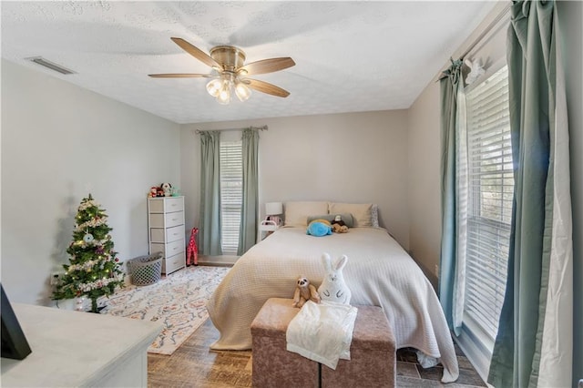 bedroom featuring hardwood / wood-style floors, a textured ceiling, and ceiling fan