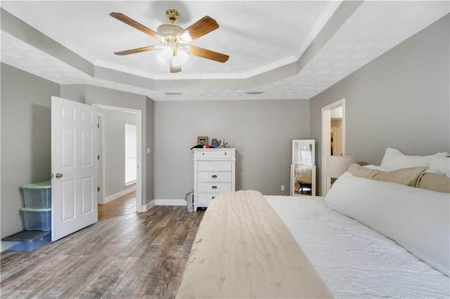 bedroom featuring hardwood / wood-style floors, a tray ceiling, ceiling fan, and ornamental molding