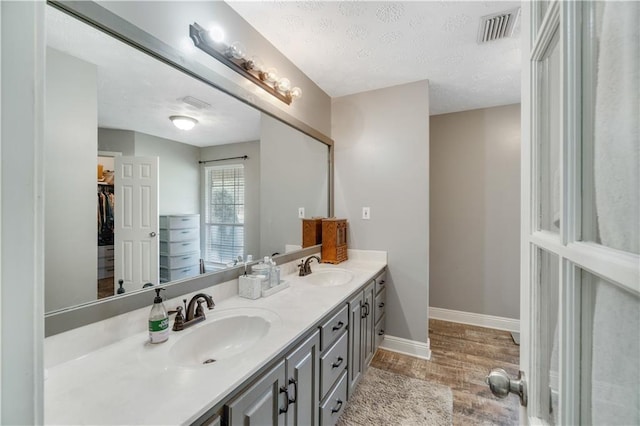 bathroom with hardwood / wood-style floors, vanity, and a textured ceiling