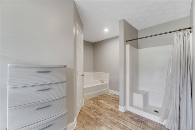 bathroom featuring hardwood / wood-style flooring and plus walk in shower