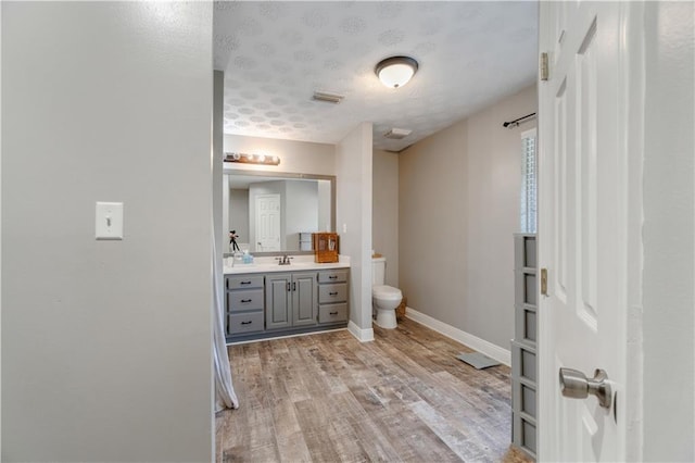 bathroom featuring wood-type flooring, vanity, a textured ceiling, and toilet