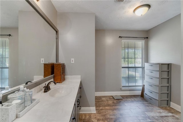 bathroom with hardwood / wood-style floors, vanity, and a textured ceiling