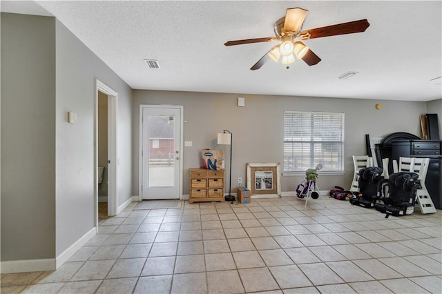 workout area with light tile patterned floors, a textured ceiling, and ceiling fan