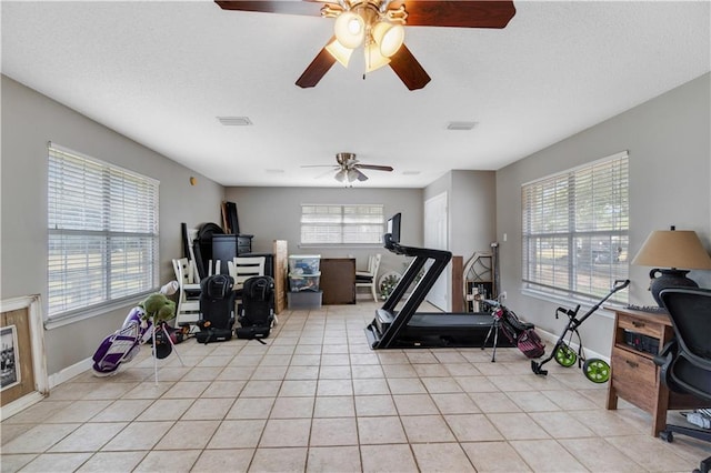 exercise area with light tile patterned floors and ceiling fan