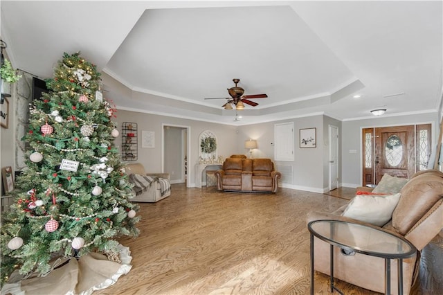 living room with ceiling fan, light wood-type flooring, crown molding, and a tray ceiling