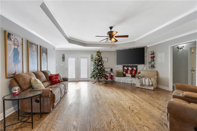 living room with french doors, ornamental molding, a tray ceiling, ceiling fan, and hardwood / wood-style flooring