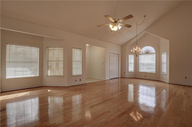 spare room featuring ceiling fan with notable chandelier, high vaulted ceiling, and light hardwood / wood-style flooring