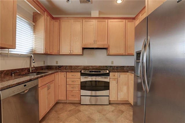 kitchen with appliances with stainless steel finishes, sink, light brown cabinetry, and dark stone counters