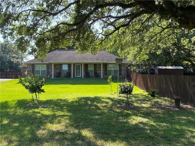 exterior space featuring brick siding, a front lawn, and fence