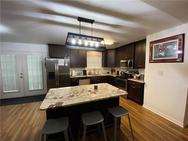 kitchen with a sink, dark wood-type flooring, a breakfast bar area, dark brown cabinets, and appliances with stainless steel finishes