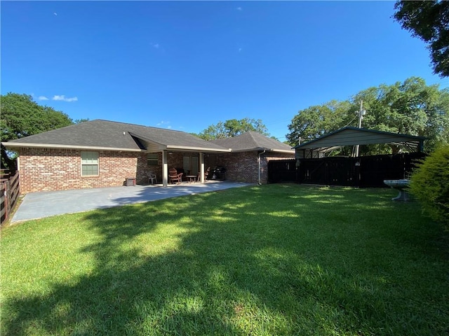 back of house featuring a yard, a patio, brick siding, and fence