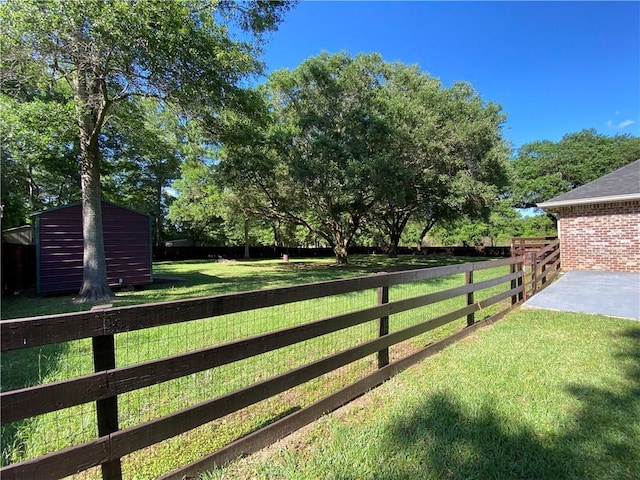 view of yard with a fenced backyard, a storage unit, and an outbuilding