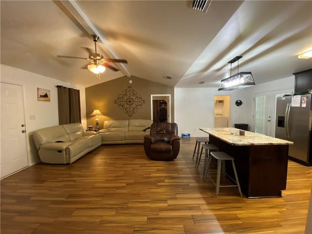 living area featuring vaulted ceiling with beams, ceiling fan, visible vents, and wood finished floors