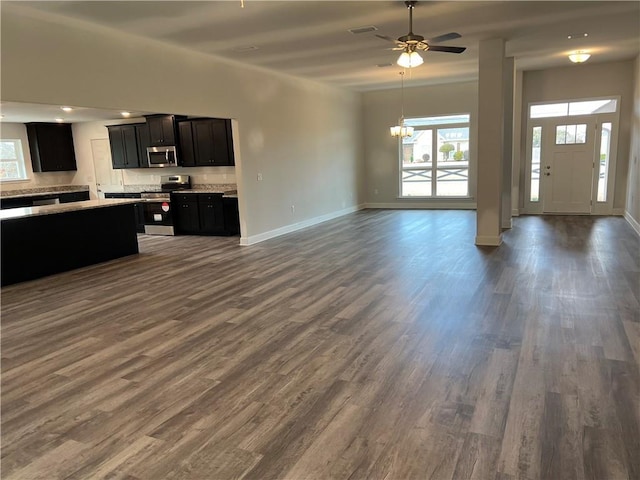 unfurnished living room with ceiling fan with notable chandelier and dark hardwood / wood-style floors