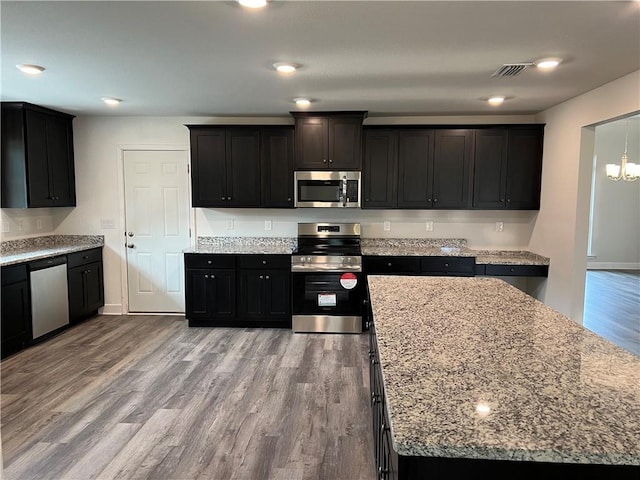 kitchen featuring stainless steel appliances, light stone counters, and light wood-type flooring