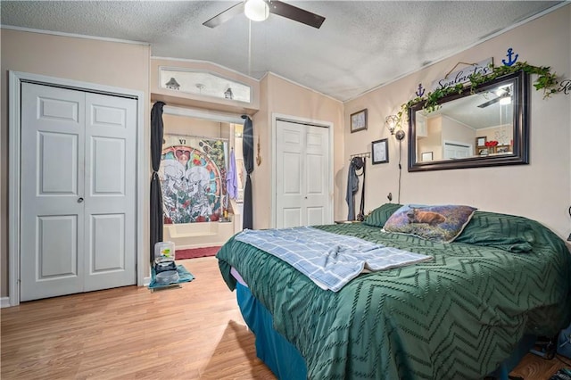 bedroom featuring a textured ceiling, multiple closets, wood-type flooring, and ceiling fan