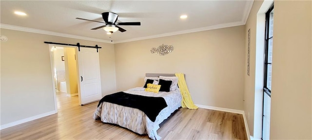 bedroom with ceiling fan, crown molding, light wood-type flooring, and a barn door