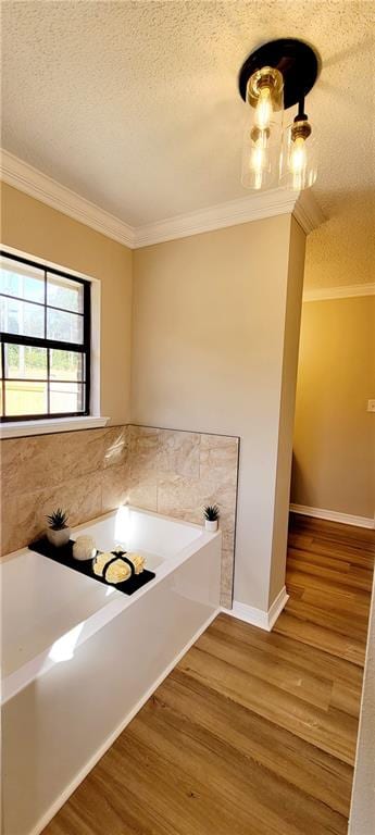 bathroom with ornamental molding, a textured ceiling, hardwood / wood-style flooring, and a tub