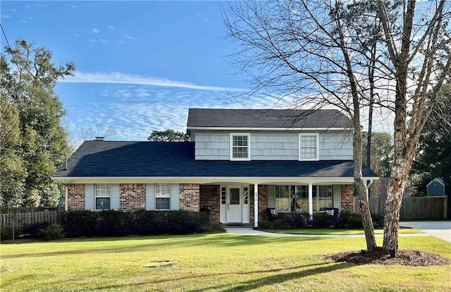 traditional-style house with brick siding, a front yard, and fence