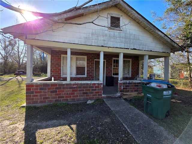 bungalow-style home featuring covered porch and brick siding