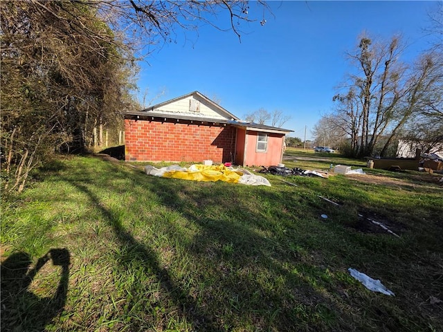 view of home's exterior featuring brick siding and a yard