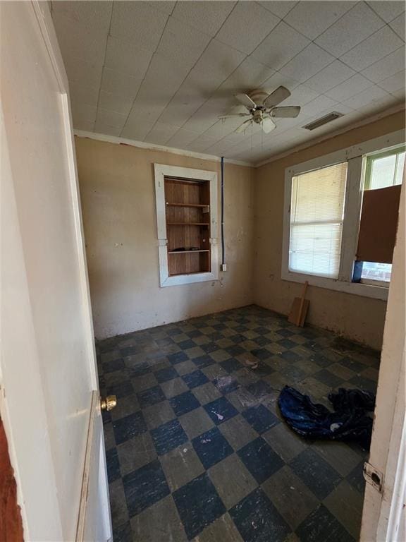 empty room featuring ceiling fan, crown molding, visible vents, and tile patterned floors