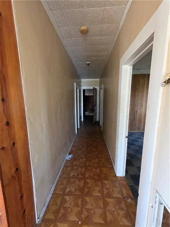 hall featuring wood walls and baseboards