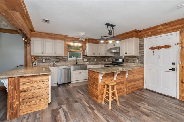 kitchen featuring kitchen peninsula, sink, light stone countertops, appliances with stainless steel finishes, and white cabinets