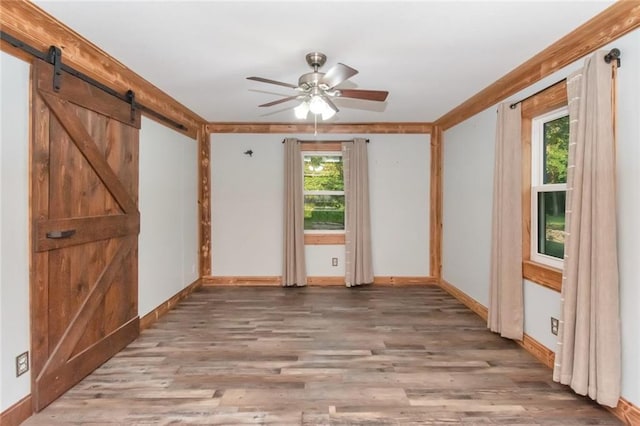 spare room featuring a barn door, ceiling fan, and hardwood / wood-style flooring